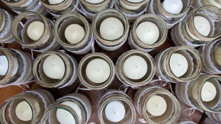 Wedding decoration - candles in glass jars decorated with lace, sackcloth and ribbons over wooden...