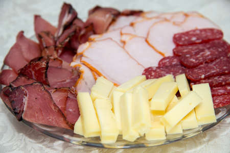 Different types delicacies of meat and cheese arranged in a plate over light background - selective focusの写真素材