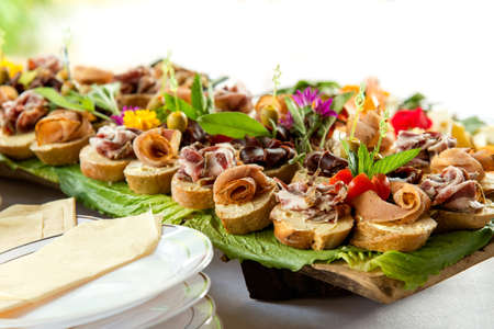 Close up of small canapes arranged on a plate over light background - selective focus