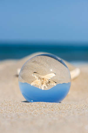 Lensball summer vacation landscape with starfish reflection. Travel and leasure concept. Selective focus, copy space.の写真素材