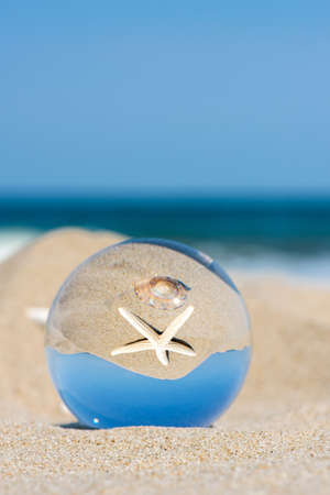 Lensball summer vacation landscape with starfish reflection. Travel and leasure concept. Selective focus, copy space.の写真素材