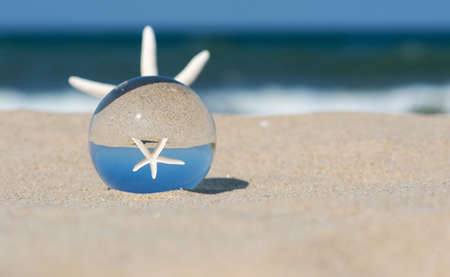 Lensball summer vacation landscape with starfish reflection. Travel and leasure concept. Selective...