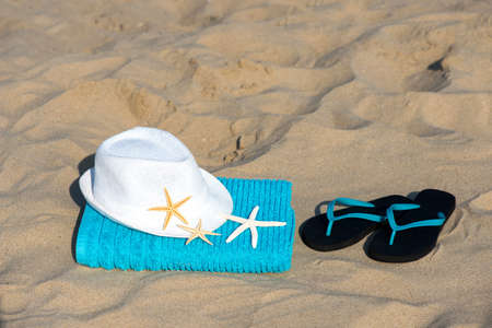 Summer vacation concept  towel with straw hat and starfish on sandy tropical beach