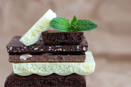 Different kinds of chocolates with nuts cocoa powder and mint - selective focus, wrapping brown...