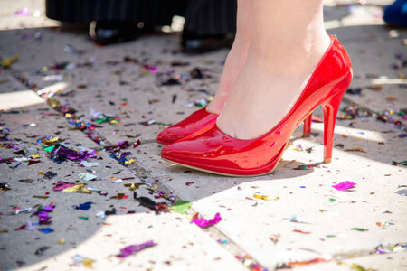 female legs in red high heels shoes against the confetti and garlands - selective focus, party conceptの写真素材