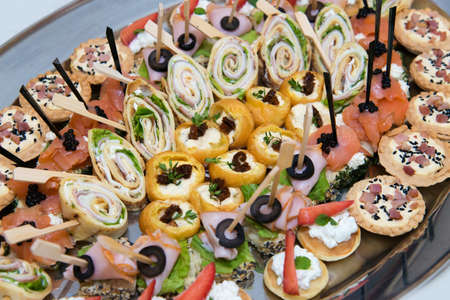 Catering food for the event - different types delicacies of meat and cheese arranged in a plate over...