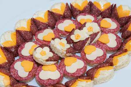 Catering food for the event - different types delicacies of meat and cheese arranged in a plate over...