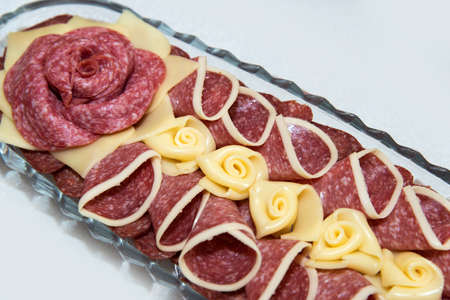 Catering food for the event - different types delicacies of meat and cheese arranged in a plate over...