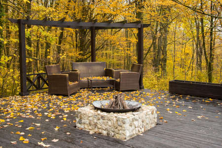 Cozy Autumn patio with chairs, hearth and firewoods.Exterior in backyard for relax in autumn garden....