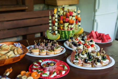 The buffet at the reception. Assortment of canapes on wooden board. Banquet service. Catering, snacks with different types of cheese and meat. Party Concept.の写真素材