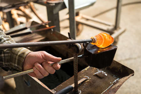 Glass blowing The hands of the craftsman working with molten glass Traditional crafts