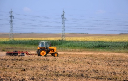 Ploughing tractor at field cultivation work の写真素材
