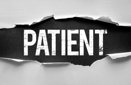 Grunge-style image with the word "PATIENT" revealed beneath torn paper. Ideal for healthcare, patience, personality traits, hospitals, or therapy-related concepts and themesの写真素材