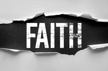 The word "FAITH" appears in bold, distressed white letters revealed through torn paper on a dark background. A symbolic concept image representing belief, spirituality, and inner strengthの写真素材