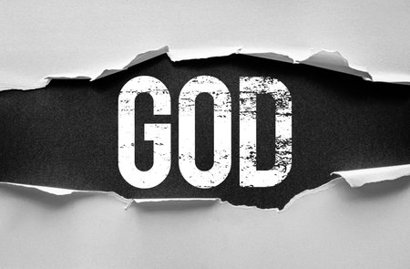 Word "GOD" revealed beneath torn paper in a bold, grunge style. High-contrast design with distressed white text on dark background symbolizes faith, belief, and spiritual powerの写真素材
