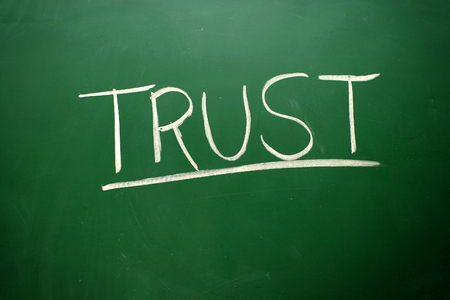Handwritten Trust word with white chalk on a blackboardの写真素材