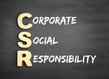 Wooden alphabets building the word CSR - Corporate Social Responsibility acronym on blackboardの写真素材