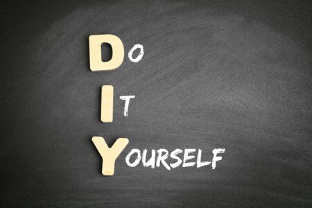 Wooden alphabets building the word DIY - Do It Yourself acronym on blackboardの写真素材