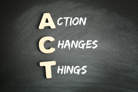 Wooden alphabets building the word ACT - Action Changes Things acronym on blackboardの写真素材