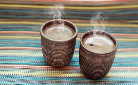 two clay cups with coffee on the color backgroundの写真素材