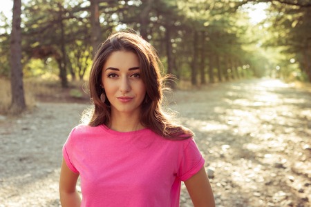 portrait of beautiful young woman in shorts against the sun background standing on stone pathの写真素材