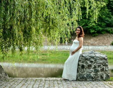 cute pregnant woman standing in the parks. on background the sunset warm weatherの写真素材