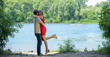 Young and cute happy couple hugging and laughing on river backgroundの写真素材