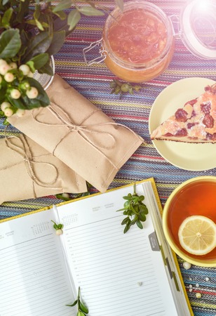 cherry pie, tea, glass jar of honey and other decorations on the colorful tablecloth. sunlightの写真素材
