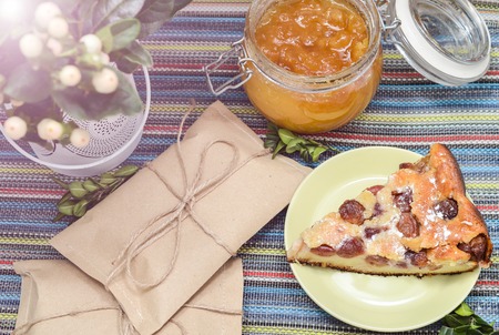 cherry pie green twig, honey and envelope on the colorful tablecloth. sunlightの写真素材