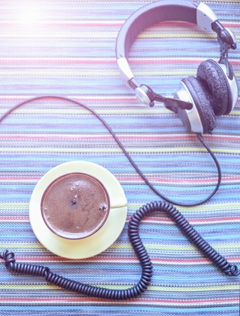 big headphones and cup with coffee on the colorful tablecloth