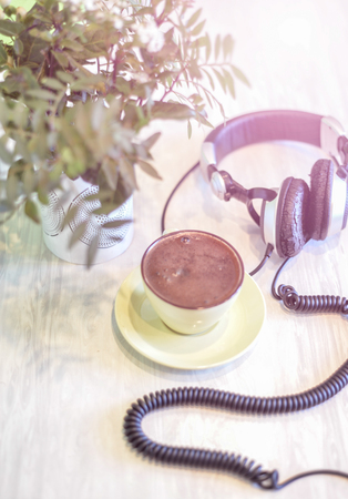 big headphones and cup with coffee on the colorful tableclothの写真素材