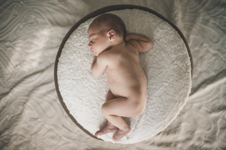 A nude newborn baby is laying down sleeping.の写真素材