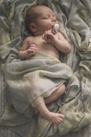 sleeping newborn baby laying on the bed wrapped in the scarf. Sepia Tonedの写真素材