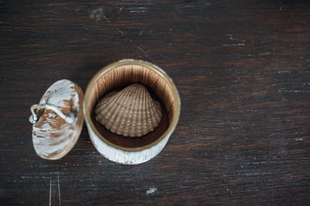 small conch in the small box on the old brown wooden tableの写真素材