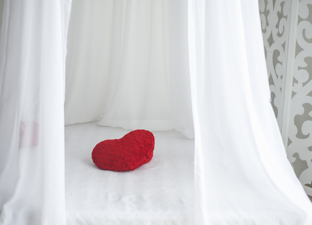 red hearts shape pillow on white bed sheetの写真素材