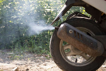 smoke from the exhaust pipe of a scooterの写真素材