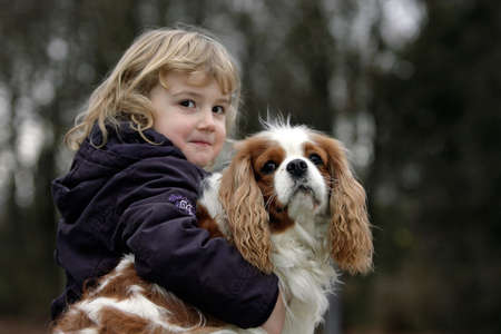 young blond girl hugging her spaniel dogの写真素材