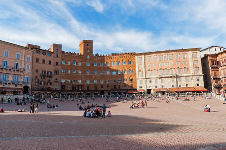 Unidentified tourists sunbathing on Piazza del Campo in Siena - Italy. Piazza del Campo is the principal public space of the historic center of Siena.のeditorial素材