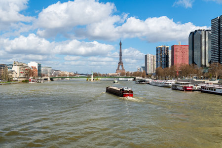 Paris, France - March 13 2020: Barges on Seine river with Eiffel Tower, Liberty Statue, Front de Seine and Pont de Grenelle in the backgroundのeditorial素材