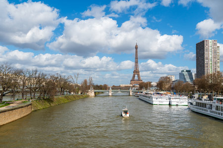 Paris, France - March 13 2020: Small boat on Seine river with Eiffel Tower, Pont Rouelle, Metro traffic and ile aux cygnes in the backgroundのeditorial素材