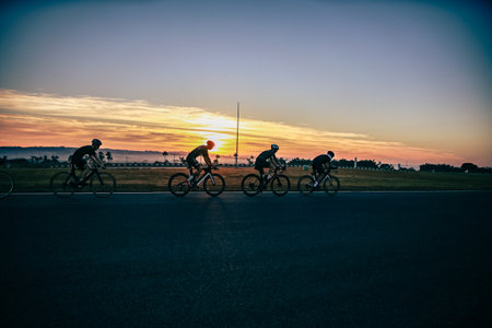 Group of cyclists riding on the road in the evening at sunset.の写真素材