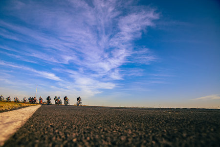 Cyclists on the road with blue sky and clouds in the backgroundの写真素材