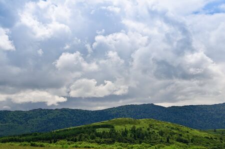 Pasture against mountains and cloudsの写真素材