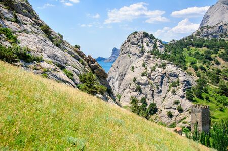 Green lawn against the high rock and the blue sky with clouds, Towerの写真素材
