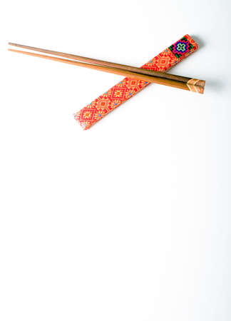 Pair of wooden chopsticks in red cover isolated on a white backgroundの写真素材