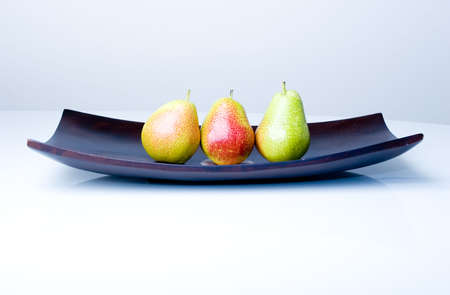 Three delicious fresh colorful pears in a wooden vaseの写真素材