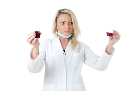 Beauty lab worker holding and comparising two test tubes with red liquidsの写真素材