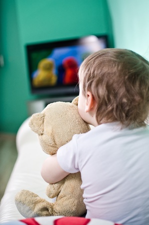 Kid with teddy bear watching TVの写真素材