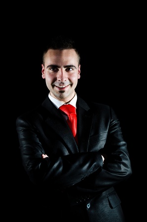 Portait of smiling young businessman in suit on  black backgroundの写真素材