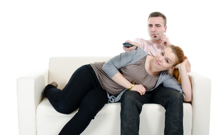 Man and woman watching TV on sofa - isolated on white backgroundの写真素材